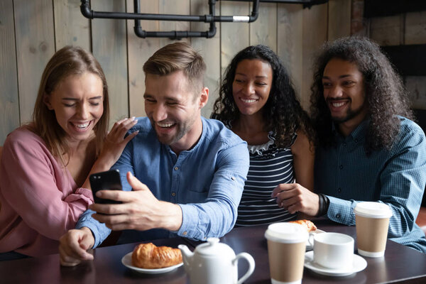 Smiling diverse friends have fun meeting for coffee in cafe