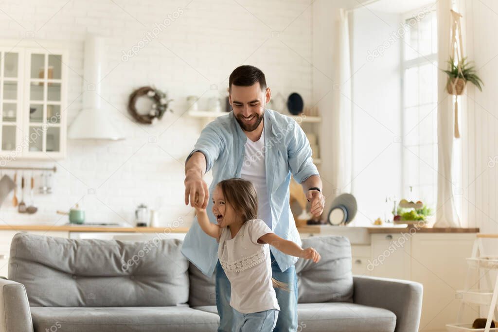 Active young father dancing to music with daughter.