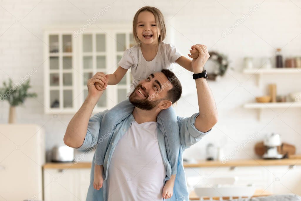 Cheerful dad carrying on neck happy little daughter.