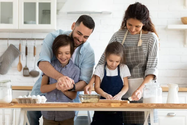 Gelukkig duizendjarig getrouwd paar onderwijzen kleine kinderen het maken van zelfgemaakt gebak. — Stockfoto