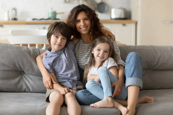 Porträtt av leende ung mamma omfamnande liten son dotter. — Stockfoto