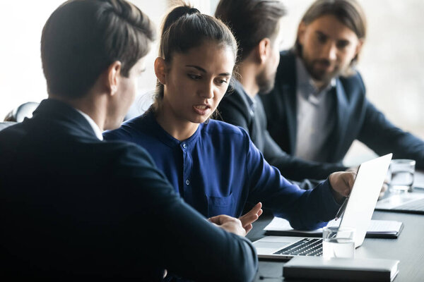 Confident businesswoman mentor training intern, using laptop in boardroom