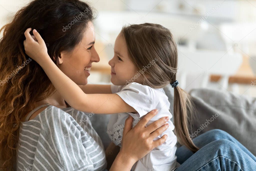 Smiling little girl running hands through mommy s hair.