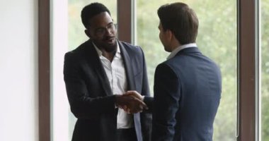 Mutlu çift ırklı göz giysisi yöneticisi motive bir partnerle tokalaşıyor..