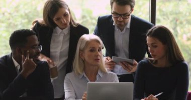 Kendine güvenen olgun iş kadını proje araştırma sonuçlarını takım arkadaşlarına gösteriyor.