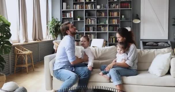 Padres felices jugando con lindas hijas pequeñas en la sala de estar — Vídeos de Stock