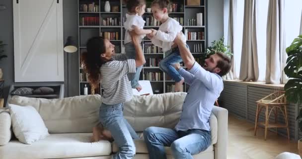 Счастливые родители играют с милыми детьми дочери в гостиной — стоковое видео