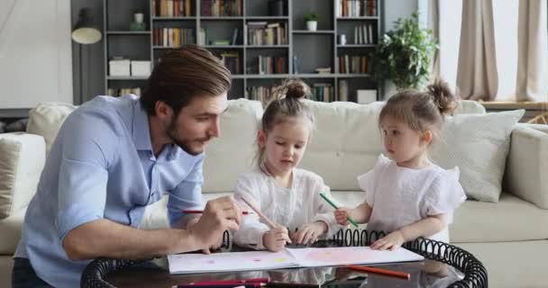 Ευτυχισμένος μπαμπάς παίζει με αξιολάτρευτο κόρες σχέδιο στο σπίτι τραπέζι — Αρχείο Βίντεο