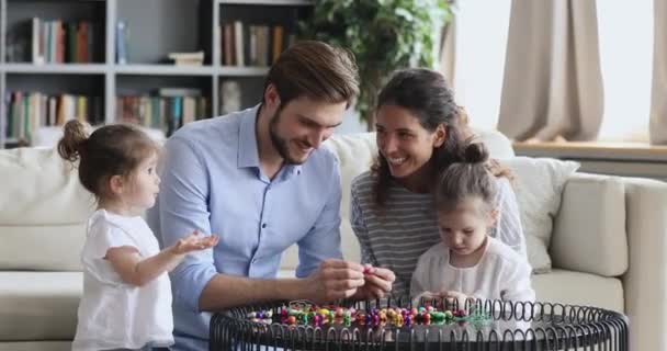 Ευτυχισμένοι γονείς με μικρά παιδιά κόρες παίζουν παιχνίδι στο σπίτι — Αρχείο Βίντεο