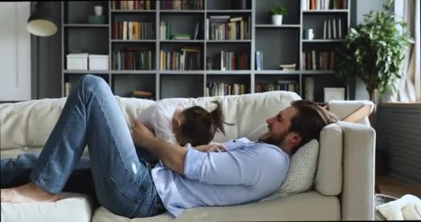 Счастливые милая дочь и папа весело щекотать на диване — стоковое видео