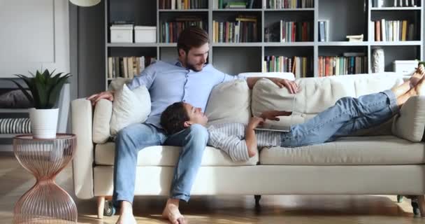 Χαλαρωμένα Millennial lounge ζευγάρι στον καναπέ χρησιμοποιώντας φορητό υπολογιστή μαζί — Αρχείο Βίντεο