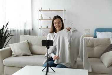 Gülümseyen kız internetten alışveriş videosu kaydediyor.