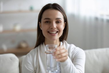 Gülümseyen genç kadın maden suyu içmeyi öneriyor.