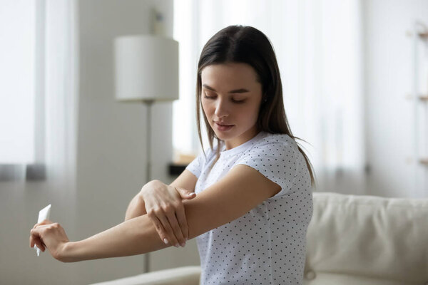 Молодая женщина наносит увлажняющий крем для тела дома
