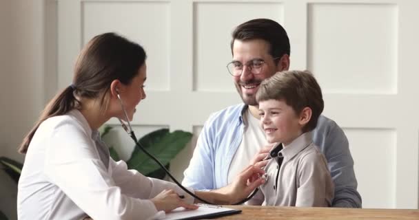 Pai segurando no colo filho pequeno, visitando pediatra . — Vídeo de Stock