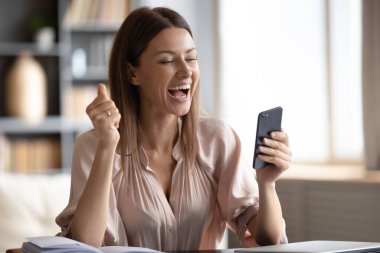 Heyecanlı kadın telefon ekranına bakıyor, online galibiyeti kutluyor