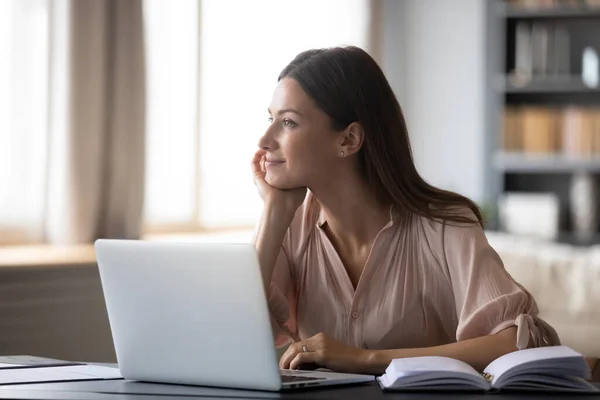 Dromerige jonge vrouw nadenken ideeën, zitten aan het bureau met laptop — Stockfoto
