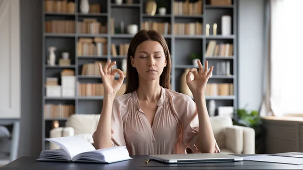 Rustige mooie vrouw met gesloten ogen mediteren, zitten aan het bureau — Stockfoto
