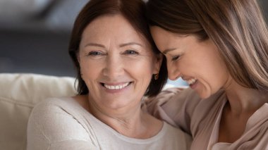 Gülümseyen olgun anne-kız kucaklaşmaları, başlarını okşamaları.