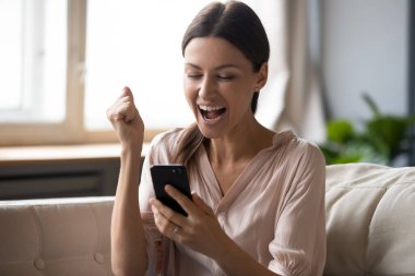 Heyecanlı kadın telefon ekranına bakıyor ve galibiyeti kutluyor.