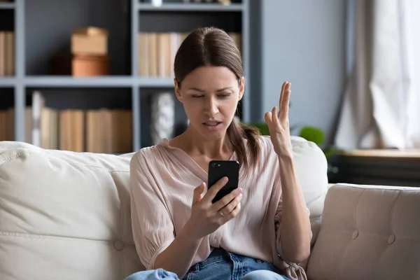 Confused angry young woman having problem with phone — Stock Photo, Image