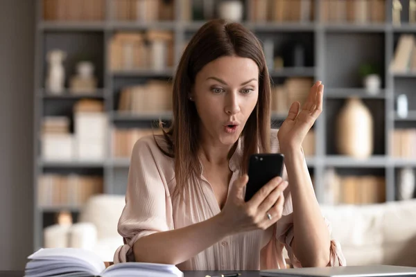 Surprised woman with open mouth looking at phone screen