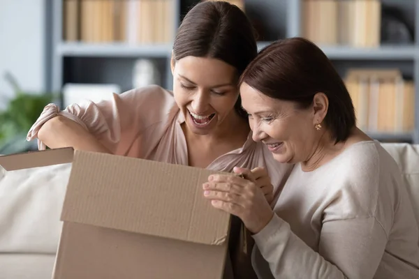 Sürpriz orta yaşlı anne ve yetişkin kız birlikte paketleri açıyor. — Stok fotoğraf