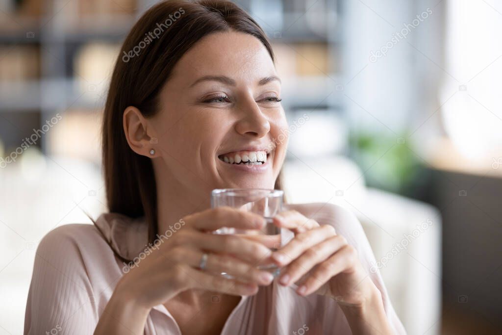 Smiling beautiful woman holding glass of pure mineral water