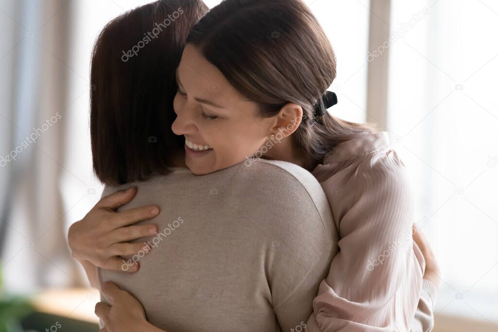 Smiling young woman with closed eyes hugging mature mother