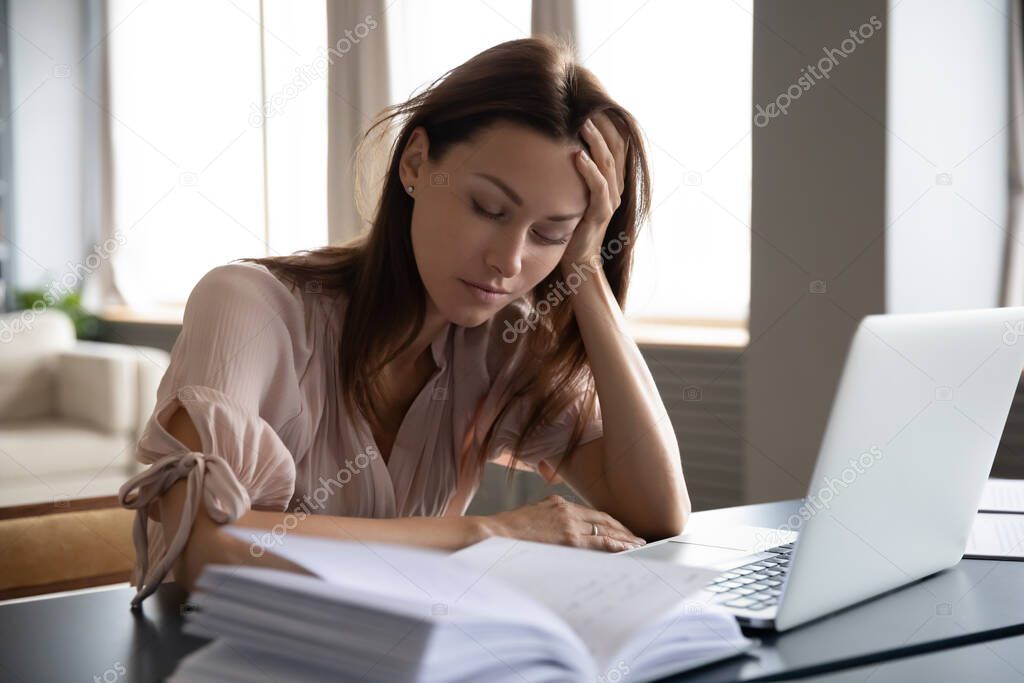 Tired sleepy woman sitting at desk with laptop, holding head