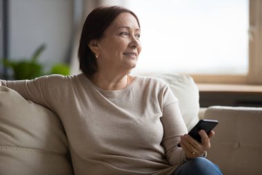 Hayalperest orta yaşlı kadın koltukta dinleniyor, elinde telefonla.