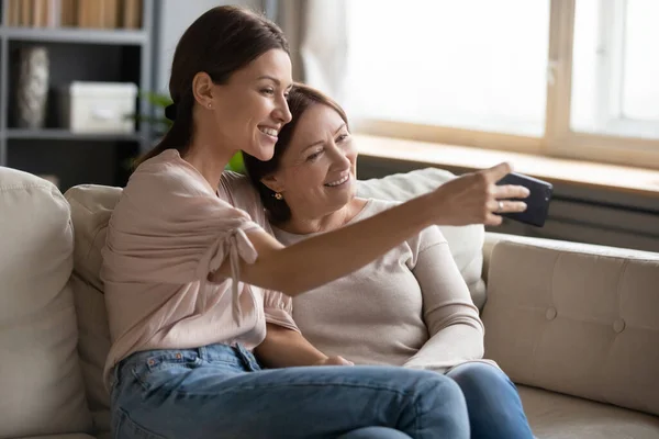 Sonrientes de mediana edad madre e hija tomando selfie juntos — Foto de Stock
