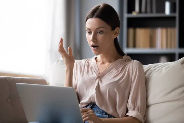 Zszokowana młoda kobieta patrząca na ekran laptopa, niespodziewane wieści — Zdjęcie stockowe