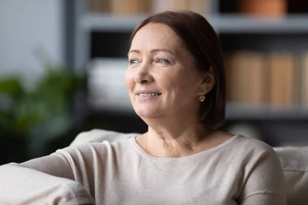 Dromerige glimlachende vrouw van middelbare leeftijd die aan een goede toekomst denkt — Stockfoto