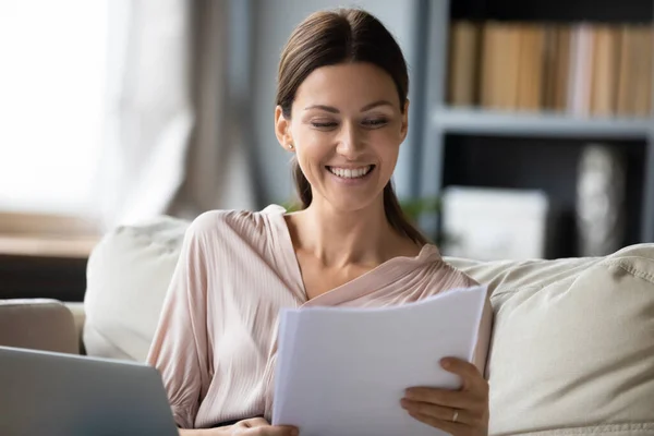 Donna sorridente che legge buone notizie nella lettera o nei documenti cartacei — Foto Stock