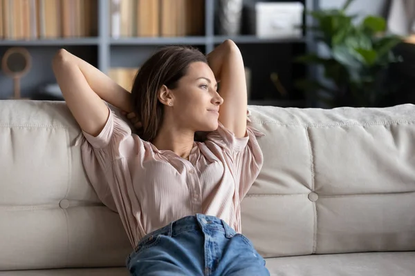 Мирная молодая женщина отдыхает дома на диване — стоковое фото