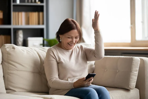 Heyecanlı orta yaşlı kadın iyi haberler okuyor, telefon kullanıyor. — Stok fotoğraf