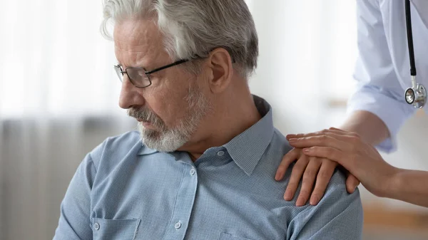 Female doctor hands touching shoulder of depressed old patient, closeup — Stock Photo, Image