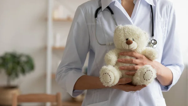 Vrouwelijke kinderarts houdt teddybeer in handen, close-up uitzicht — Stockfoto