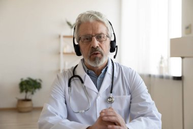 Yaşlı doktor video konferansında sanal hastaya danışmanlık yapıyor.