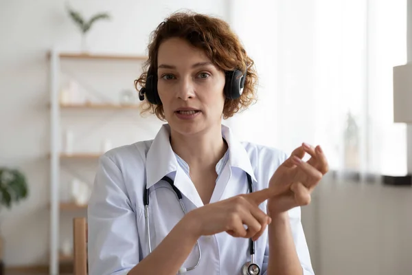 Femmina medico professionista indossando auricolare parlando guardando la fotocamera — Foto Stock