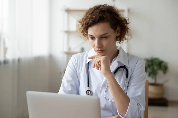 Bilgisayarda çalışan konsantre genç kadın doktor online araştırma yapıyor. — Stok fotoğraf