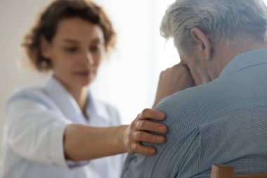 Kadın doktor omuzlarına dokunuyor üzgün yaşlı hastayı rahatlatıyor, yakın plan.