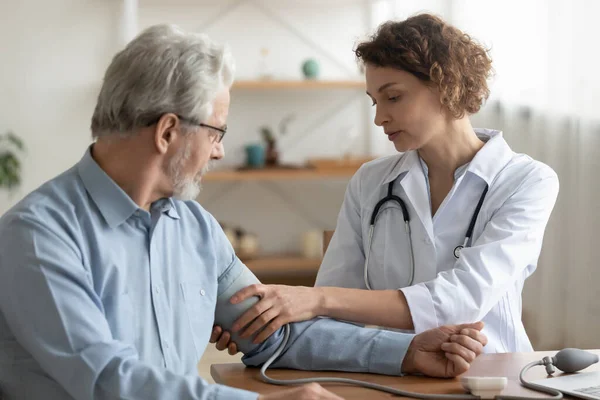 病院で高齢患者の血圧を測定する女性医師 — ストック写真