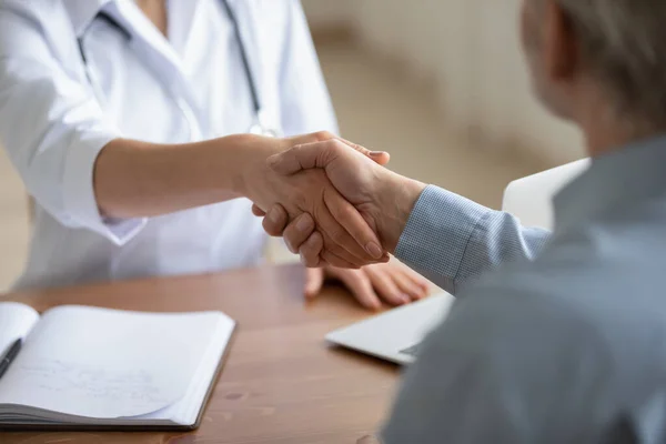 Female doctor and senior patient shake hands, close up view — Stock Photo, Image