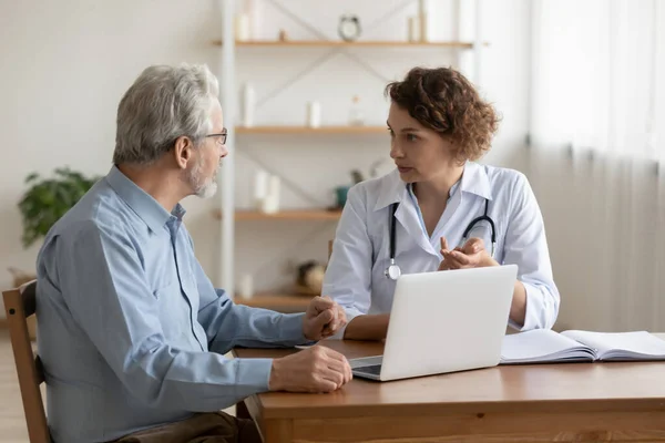 Vrouwelijke professionele arts die de behandeling van geriatrische ziekten uitlegt aan oudere patiënten — Stockfoto