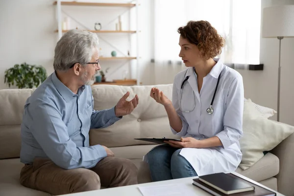 Vrouwelijke arts adviseert senior patiënt tijdens huisbezoek medische zorg — Stockfoto