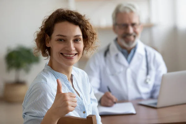 Удовлетворенная здоровая женщина пациент смотрит в камеру показывая большие пальцы вверх — стоковое фото