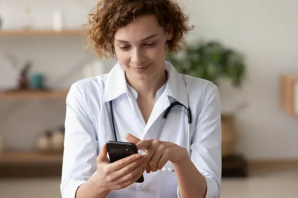 Médico joven usando aplicación móvil consultando paciente remoto en línea —  Fotos de Stock