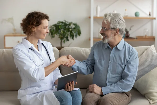 Glimlachende arts en senior patiënt handdruk tijdens medisch thuisbezoek — Stockfoto
